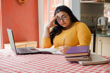 Concentrated Hispanic young woman studying online - Tired and distressed student with hand on head while studying at home - Woman with a lot of work from home