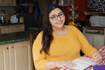 Young hispanic college student studying from home-woman working from home planning her projects-visionary woman smiling