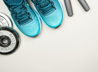 Pair of sports shoes, jump rope and dumbbells on gray background