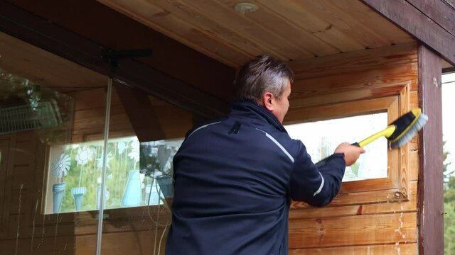 Man cleaning walls and floor with high pressure power washer. Washing terrace wood planks and cladding walls.
