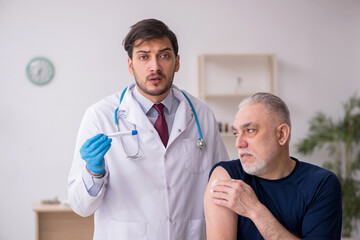 Old male patient visiting young male doctor in vaccination conce