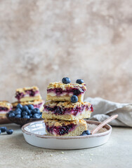 Crumble cheesecake bars with blueberry filling and fresh blueberries, concrete background. Bar slices with cheesecake, blueberry and streusel.