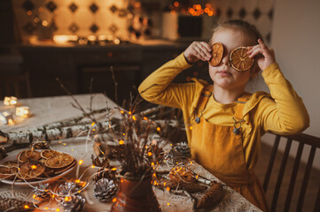 A cute sweet girl holds dry oranges instead of eyes. Crafts for the holiday