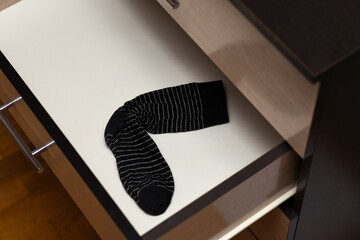 Black lost sock in an open dresser shelf