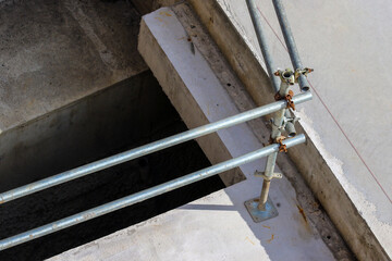Tiered stepped concrete levels in construction site. Metal safety bar handrails around deep drop....