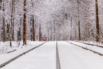 An old tram moving through a winter forest