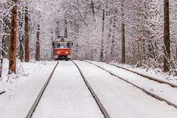 An old tram moving through a winter forest