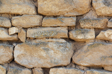 The rough textured surface of the wild stone wall. Background.