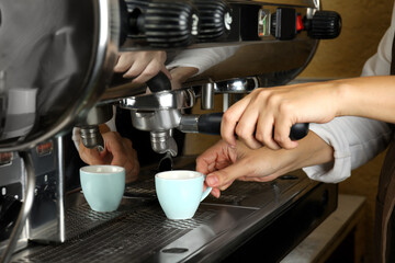Fototapeta na wymiar Barista making espresso using professional coffee machine, closeup