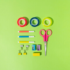 September , back to school, office concept. Various school / office supplies. Square arrangement pencils , tapes, erasers, pins, rulers, markers, paper clips . Bright green background.