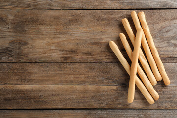 Delicious grissini sticks on wooden table, flat lay. Space for text