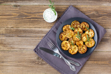 Fried slices of zucchini with sour cream sauce. Courgettes with herb for dinner on natural wooden background