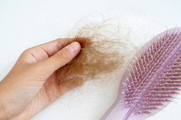bunch of hair in the hand of a young woman after combing her hair, a problem with hair loss after suffering covid, alopecia as a complication of coronavirus