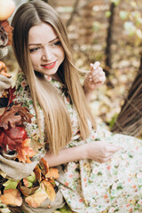 Fototapeta premium Lady enjoying being in autumn park at the nature. Beautiful caucasian blonde woman spending time alone while sitting at the decorated swing at autumn day