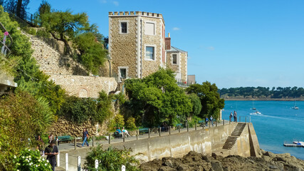 Dinard, France - September 9. 2016: View on cliff with old house tower at atlantic ocean bay...