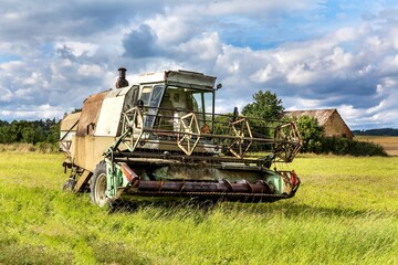 Fototapeta premium An old abandoned combine harvester in the Czech countryside. Agricultural machinery. Grain harvest.