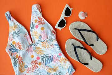 Travel and beach accessories on orange background