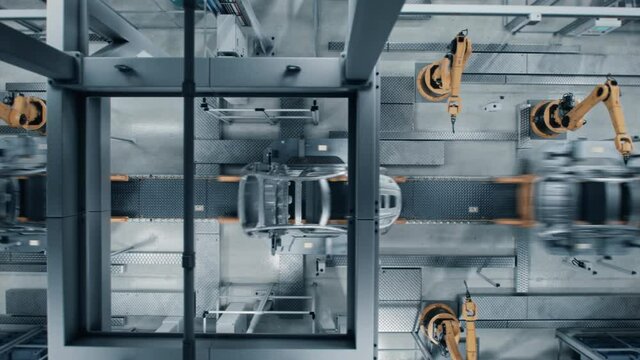 Aerial Car Factory 3D Concept: Automated Robot Arm Assembly Line Manufacturing High-Tech Green Energy Electric Vehicles. Construction, Welding Industrial Production Conveyor. Top View Time-Lapse Loop
