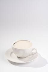 A white porcelain cup with coffee drink cappuccino on a white saucer plate on a white surface