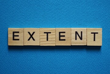 gray word extent in small square wooden letters with black font on a blue background