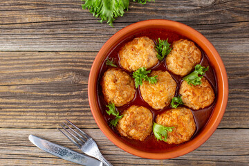 Meatballs in tomato sauce in a bowl on wooden table.