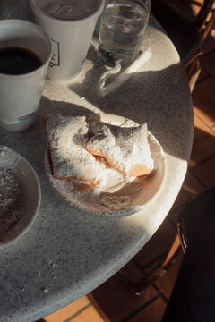Cafe au lait and beignets on a table at an outdoor cafe