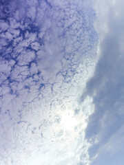 Abstract view of cloud fronts clashing overhead, fragmenting and coalescing like icebergs breaking off from a glacier, against a deep blue sky.