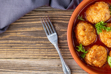 Meatballs in tomato sauce in a bowl on wooden table.