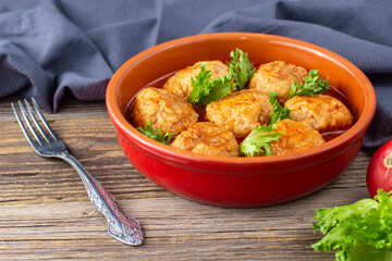 Meatballs in tomato sauce in a bowl on wooden table.