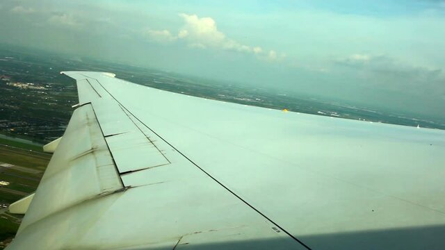 WINDOW VIEW OF WING PLANE OVER GROUND
