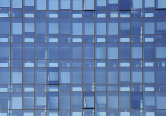Geometry and abstract reflection of the blue facade. The exterior of modern offices: structure with glass windows.
