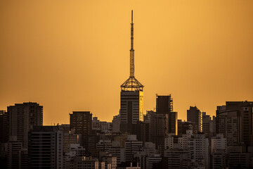 Prédios da cidade grande iluminados pelo Sol da tarde deixando o céu com tom amarelado e sombras nos prédios 