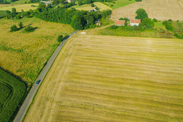 Wąska, wiejska asfaltowa droga przebiegająca przez pola uprawne. Widok z drona.