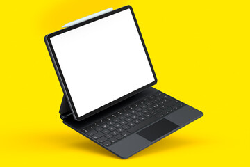 Computer tablet with keyboard and blank screen isolated on yellow background.