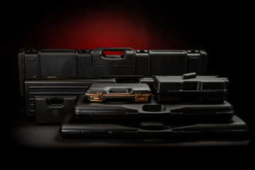 A variety of plastic cases for weapons. Strong containers for storing and transporting weapons against a dark background with a red spot of light.