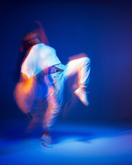 Dancing girl in white sportswear in neon studio light. Female dancer show expressive hip hop dance....