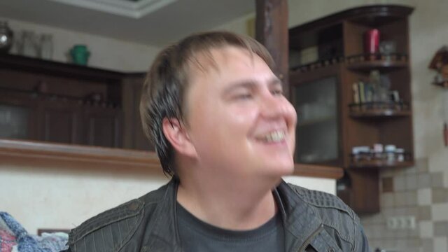 Cheerful man listens to his favorite rock music, shakes head to the beat and shows devils horns hand gesture, front view, close up. Smiling guy is having great time at party.