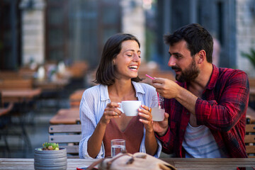 Sweet young romantic couple drinking coffee and lemonade on cafe terrace