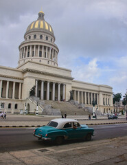 Fototapeta na wymiar Classic auto drives past the Capitolio building, Havana, Cuba.