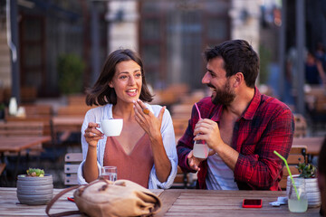 Sweet young romantic couple drinking coffee and lemonade on cafe terrace