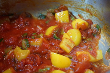 tomatoes, yellow peppers, green onions simmer in a saucepan