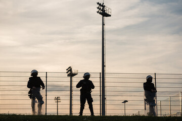 Silhouettes of policemen standing next to the football field (inscription in Polish Police)