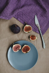 still life with ripe fresh figs with a knife and purple textiles on a table top view