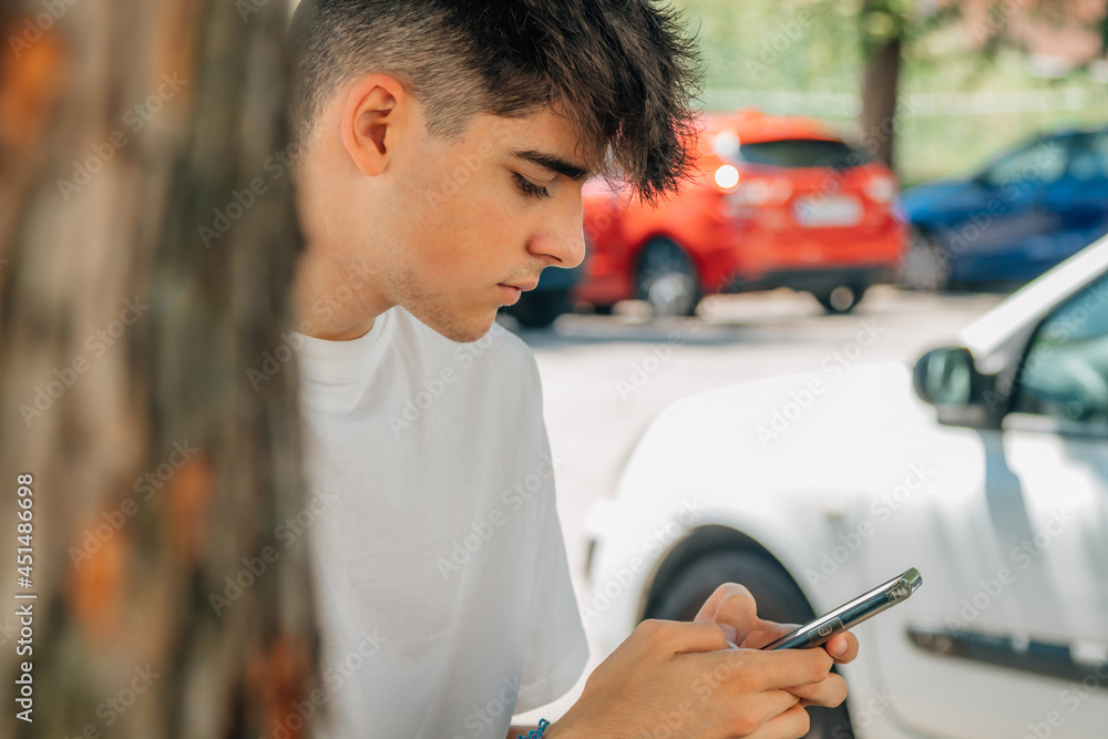 Wall mural portrait of teenage boy with mobile phone outdoors