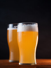 Two glasses of wheat beer on a black background