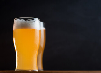 Two glasses of wheat beer on a black background copy space