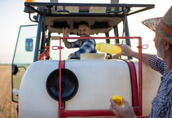 Farmer pouring chemicals in sprayer for plant protection in field
