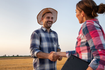 Two farmers shaking hands in field during harvest