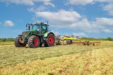 Poster Een tractor met hooischudder die het gemaaid gras in de wei draait © Wolfgang Jargstorff