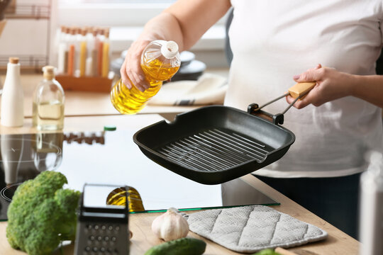 Mature Woman Pouring Oil Into Frying Pan In Kitchen